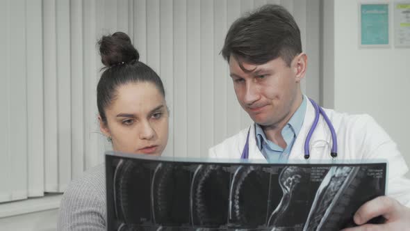 Doctor and Patient Looking at MRI Scan on Medical Appointment alt