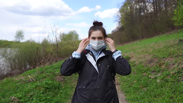 Woman in the Park in Nature Wears a Protective Mask From Viruses on Her Face