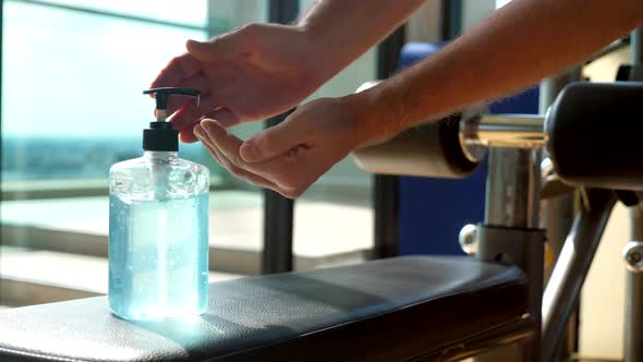 Sportsman Using Bottle of Antibacterial Soap in Gym Rubs Carefully alt