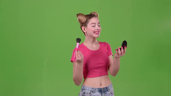 Teen Girl Holding a Brush in Her Hand and Powdering Her Cheeks. Green Screen. Slow Motion alt