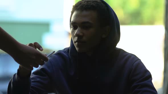 Hand proposing cigarette African-American male teenager alt