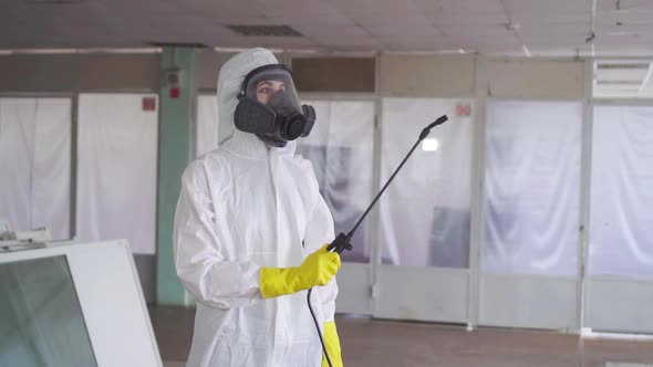 Disinfector in Special Clothes and in a Protective Mask with a Sprayer alt