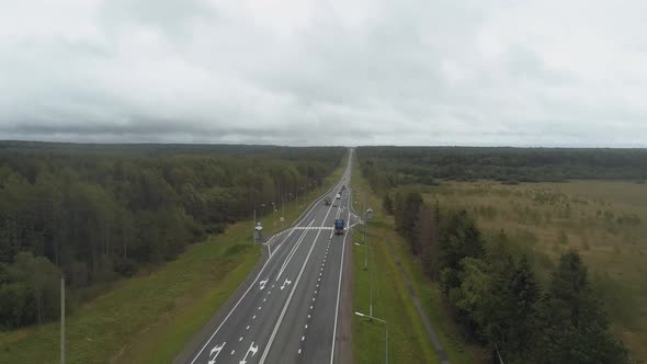 The Drone Flies Up Over a Busy Highway Behind Cars Trucks and Cars Moving in the Stream Along a