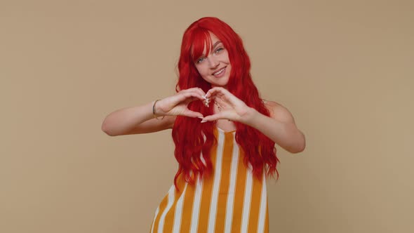 Smiling Ginger Girl Makes Heart Gesture Demonstrates Love Sign Expresses Good Feelings and Sympathy alt