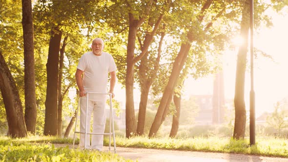 Disabled old man is walking with a walker. Handicapped patient in the park. alt