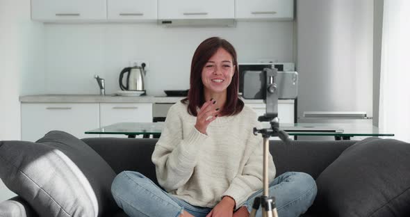 Woman Sitting in Couch Recording New Videovlog Puts Smartphone on Tripod alt