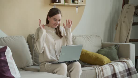 The Excited Woman Looks at the Laptop Screen Celebrates the Victory Sits on a Cozy Sofa in the alt