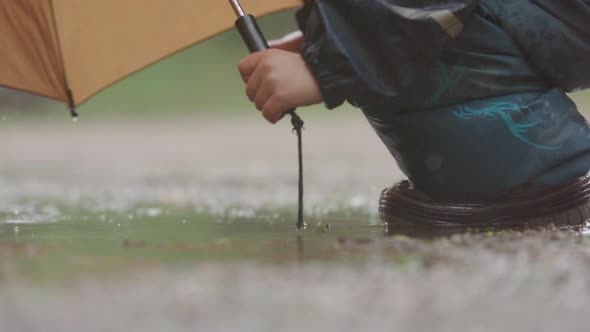 SLOW MOTION, CLOSEUP - A child jumping in the puddle during heavy rain alt