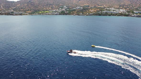 Aerial View of a Motor Boat Towing a Tube. Elounda, Crete, Greece