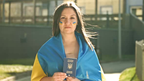 Portrait of a Woman Covered with the Flag of Ukraine with a Ukrainian Passport in Her Hands
