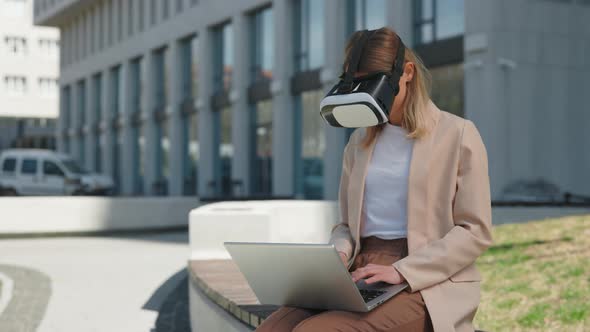 Woman in VR Headset Sitting with Laptop Near Office Building alt