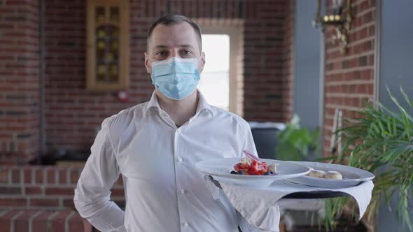 Portrait of Waiter in Covid19 Face Mask Walking with Dessert and Salad on Tray in Slow Motion alt