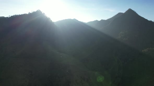 Aerial landscape view of the sun is shining through the greenery rainforest mountains by drone