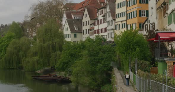 Tourist walking along path overlooking river as birds fly near in downtown Tubingen historic distric alt