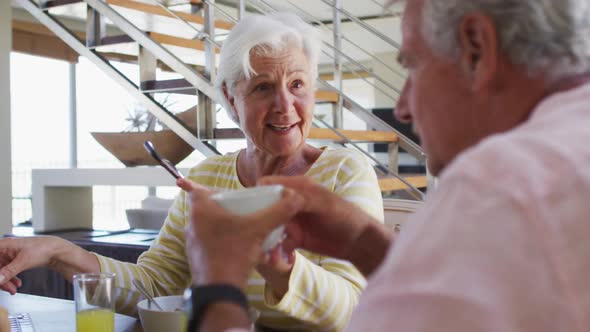 Senior caucasian couple having talking to each while having breakfast together at home alt