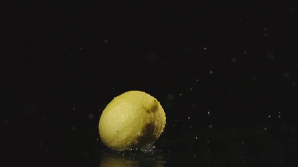 Lemon Falls In Water In Dark And Splashes Scatter In Different Directions