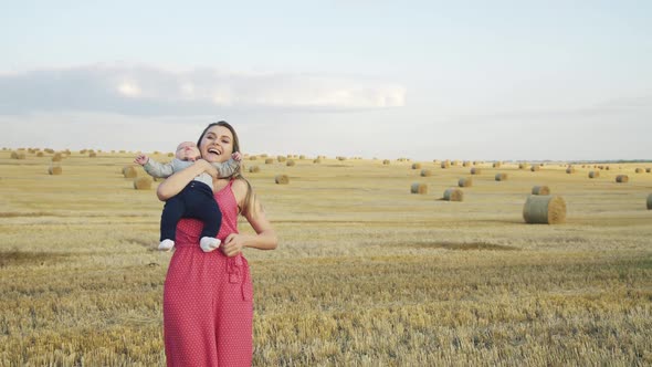 Happy Mother Rejoices in the Haystack Field When Caresses and Kisses Cute Baby alt