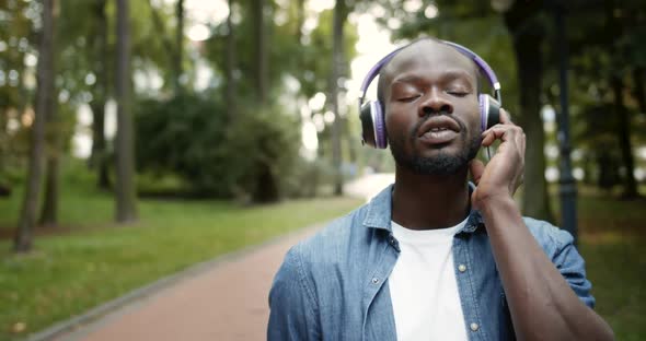 Afro-american Male in Headphones Singing in Park