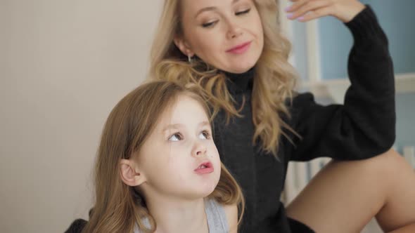 Photographer Takes Pictures Mother in a Black Sweater and a Jacket with Her Daughter at Photo Shoot alt
