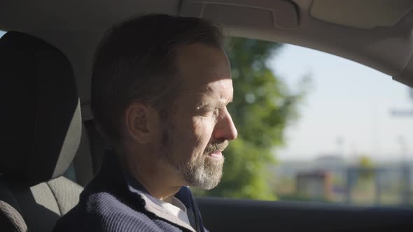 A Middleaged Handsome Caucasian Man Looks Seriously at the Camera in a Car  Closeup