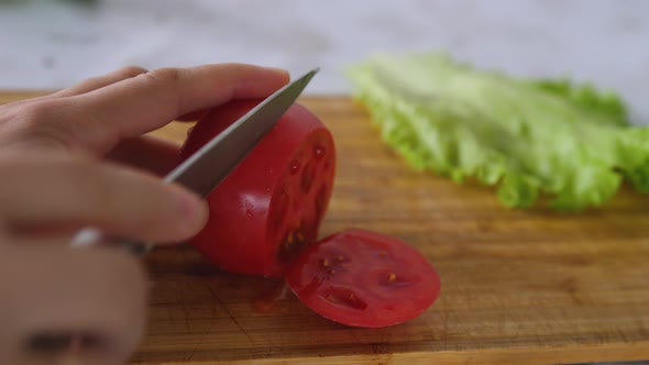 Female Hands Cut Tomato on a Cutting Board with Knife