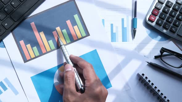 Top View of Businessman Hand Analyzing Charts on Paper  alt