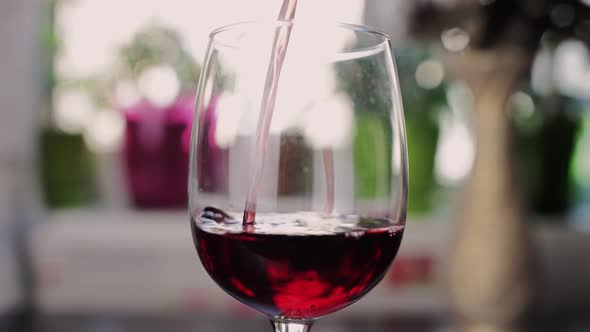 red wine is poured into a glass in the kitchen