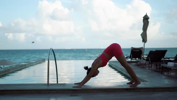 Young Attractive Woman Doing Yoga Pose Near Swimming Pool on the Sunset