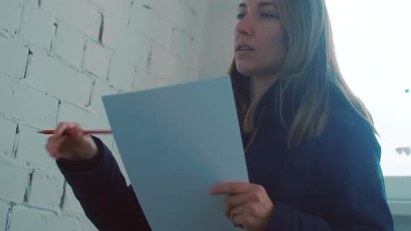 Female Designer Measuring Basement Wall and Taking Notes