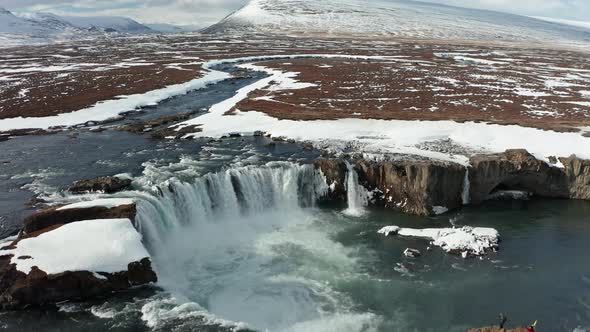 Aerial View of Godafoss Waterfall with Snowy Shore and Ice. Iceland. Winter 2019