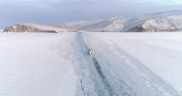 Drone Pursuing a Small Boat Icebreaker Moving on the Surface of a Frozen Lake Majestic Snow alt