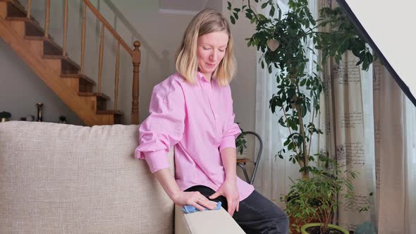 beautiful smiling woman cleaning sofa with mop in living room