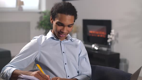 Multiracial Guy Watching Webinar Taking Educational Course Online While Sitting on Couch at Home