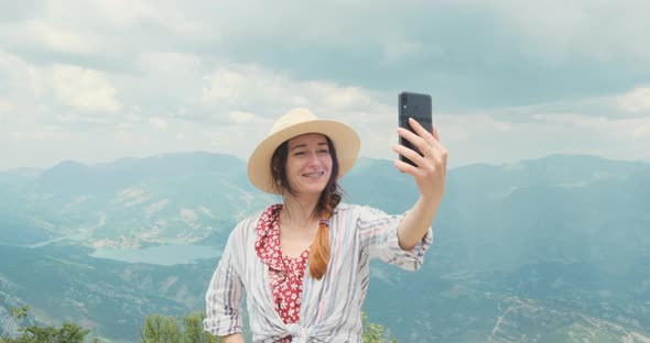 Happy Woman Traveler Having Video Call Using Smartphone in Mountains alt