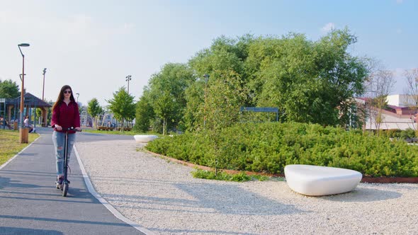 A Woman is Riding an Electric Scooter in the Park alt