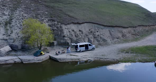 drone camping where a guy and a girl are resting near the car and tent alt
