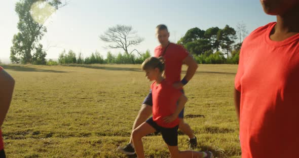 Male trainer training kids in the boot camp on a sunny day 4k