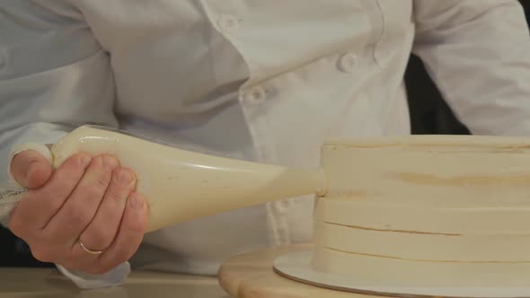 the Pastry Chef Squeezes the Cream Onto the Cake Blank