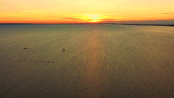 Aerial view. Kite surfing on the blue sea in the background of beautiful clouds. Sunset alt