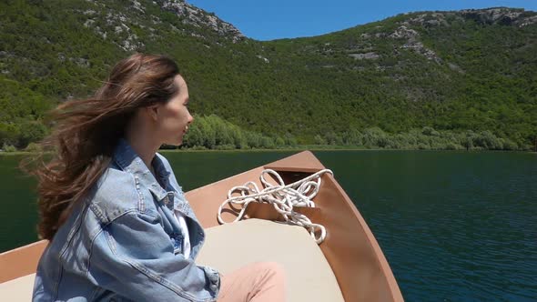 Young Woman Sits in a Motorboat and Enjoys a Ride on a Sunny Day