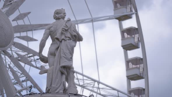 Male sculpture and rotating ferris wheel alt