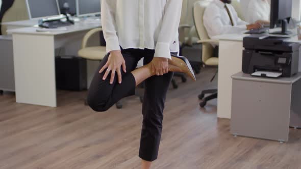 Caucasian Businesswoman Stretching Her Legs in Office alt