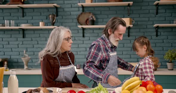 Senior Grandparents Couple with Granddaughter Cooking in Kitchen alt