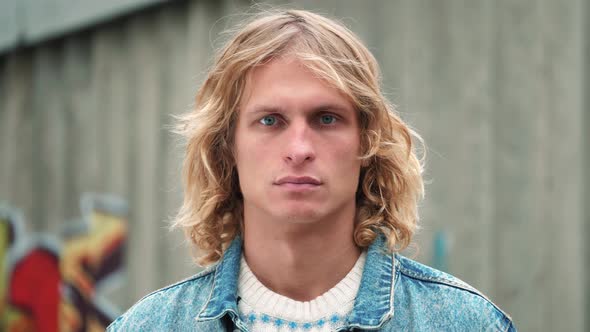 portrait of handsome blue-eyed guy with blond long curly hair