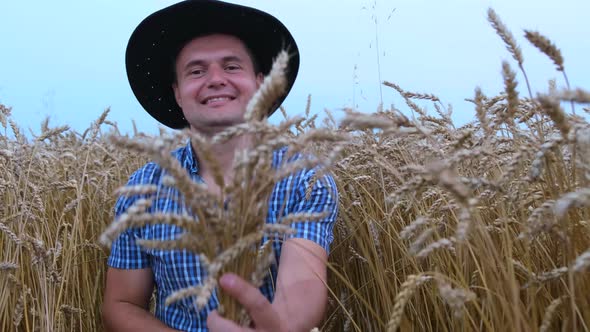 A young farmer, holding spikelets in his hands, rejoices in a good harvest. alt