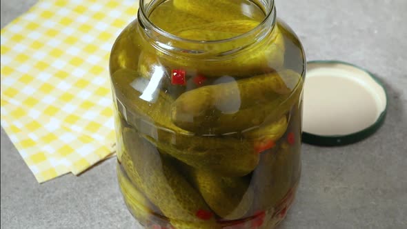 Picking a pickled cucumber from a large jar   alt