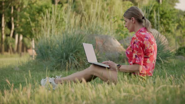 A Middleaged Woman Works Using Her Laptop in a Public Park