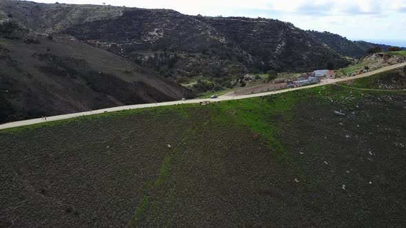 Wide aerial view of runners who are jogging on a path on the side of the mountain in Akamas in Cypru alt