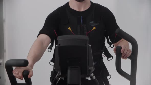 Handsome Man Wearing Electrostimulation Suit and Training on Exercise Bike alt