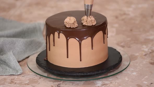 Female Hands Decorate a Sponge Cake with Chocolate Cream From a Pastry Bag
